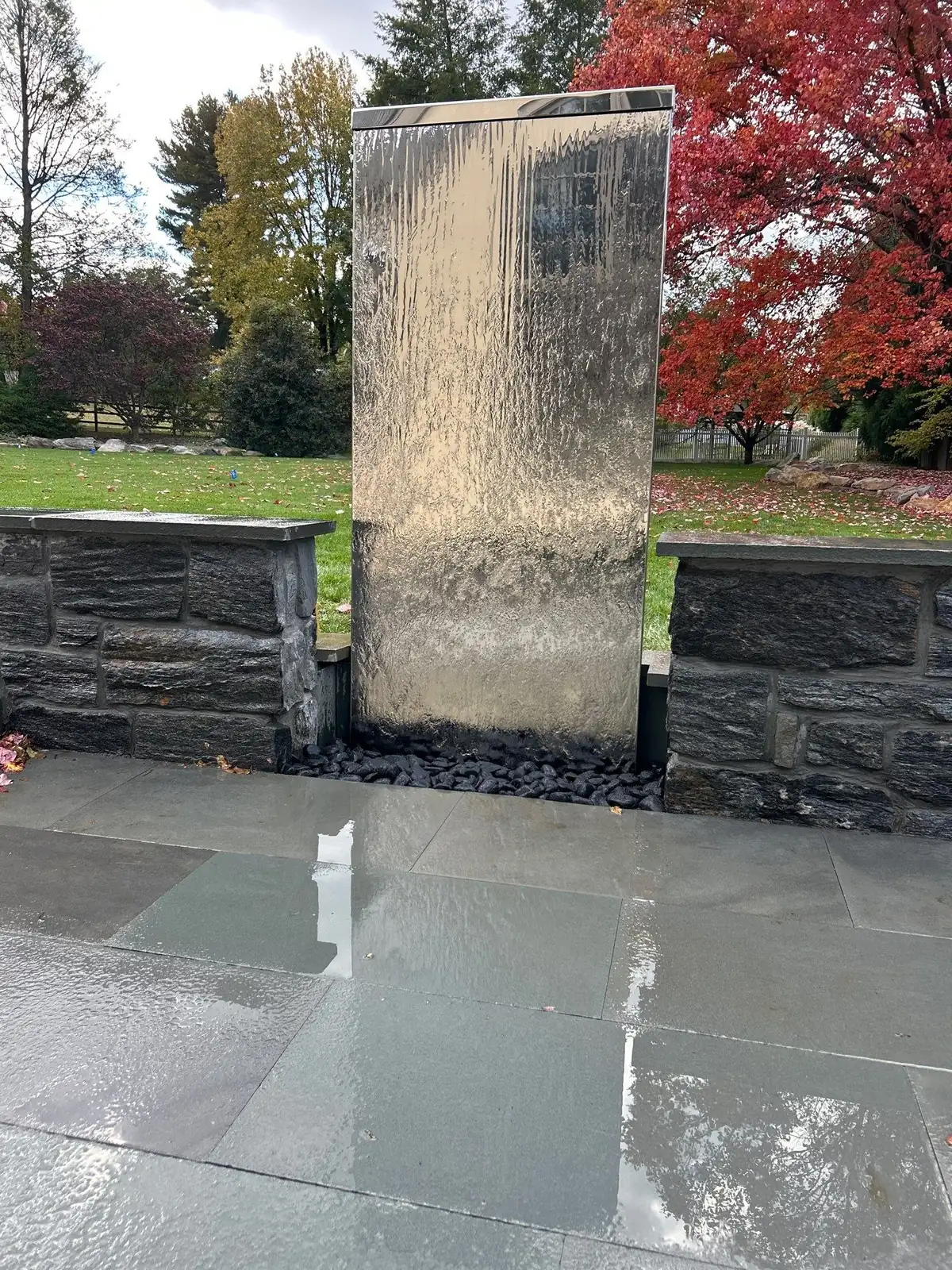 Pondless waterfall with natural boulders in residential backyard